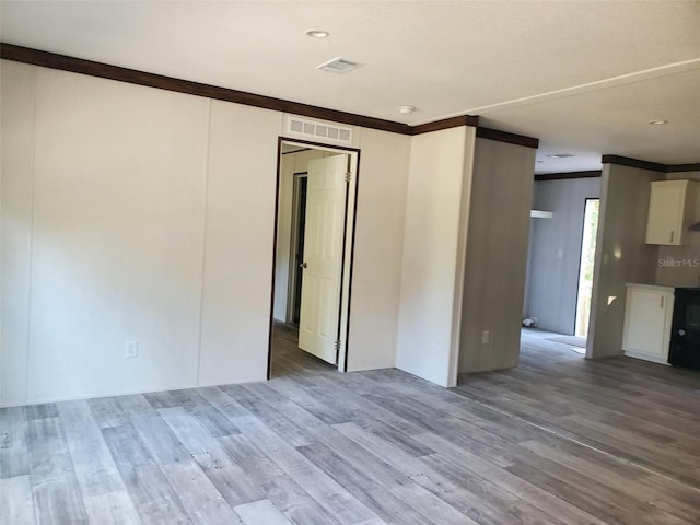 empty room with hardwood / wood-style floors and crown molding