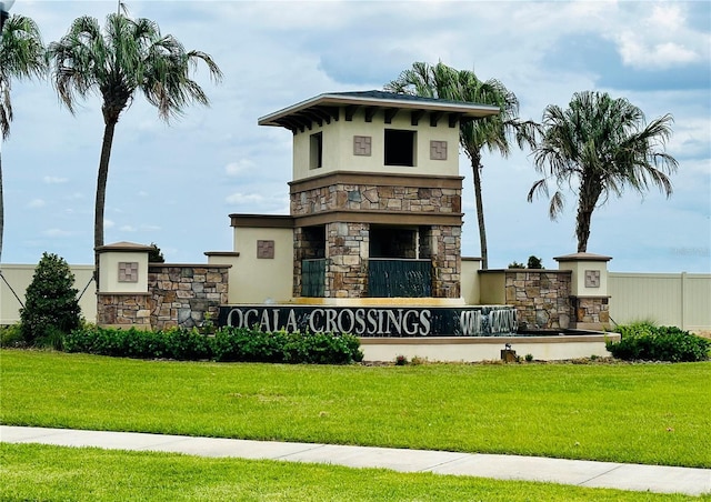 community / neighborhood sign featuring a lawn and fence