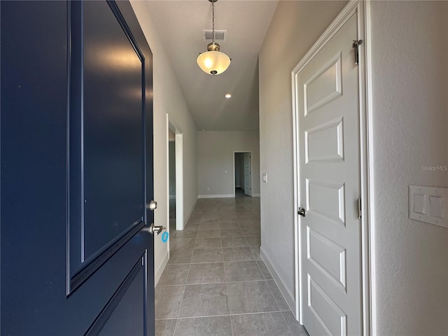 corridor with light tile patterned floors, visible vents, baseboards, and a textured wall