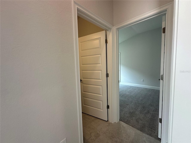 corridor featuring baseboards and carpet