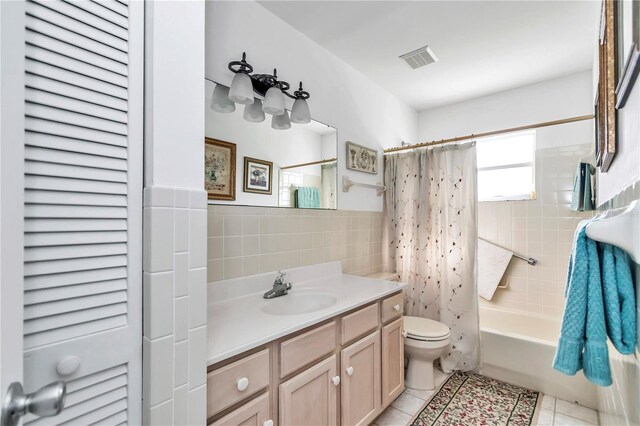 full bathroom with vanity, tile patterned floors, tile walls, shower / bath combo, and toilet