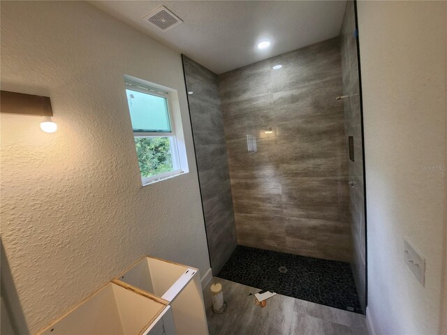 bathroom with hardwood / wood-style flooring and a tile shower