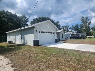 view of property exterior with a garage, a lawn, and central AC