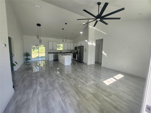 kitchen with hanging light fixtures, white cabinets, a kitchen island, stainless steel appliances, and ceiling fan