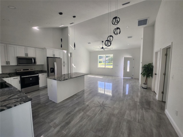 kitchen with ceiling fan, hanging light fixtures, high vaulted ceiling, white cabinetry, and appliances with stainless steel finishes