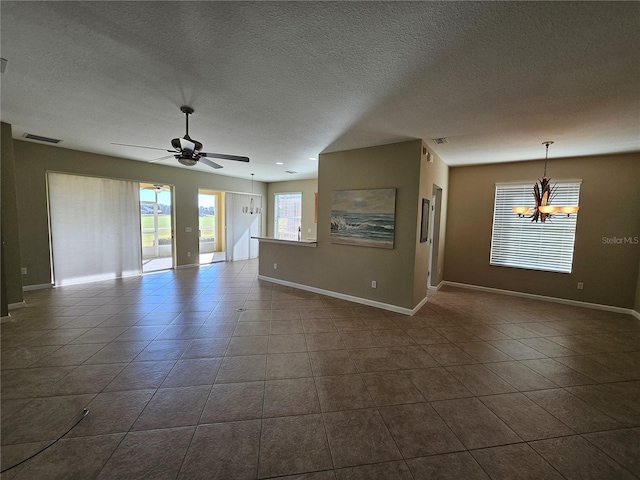 tiled empty room with ceiling fan with notable chandelier and a textured ceiling