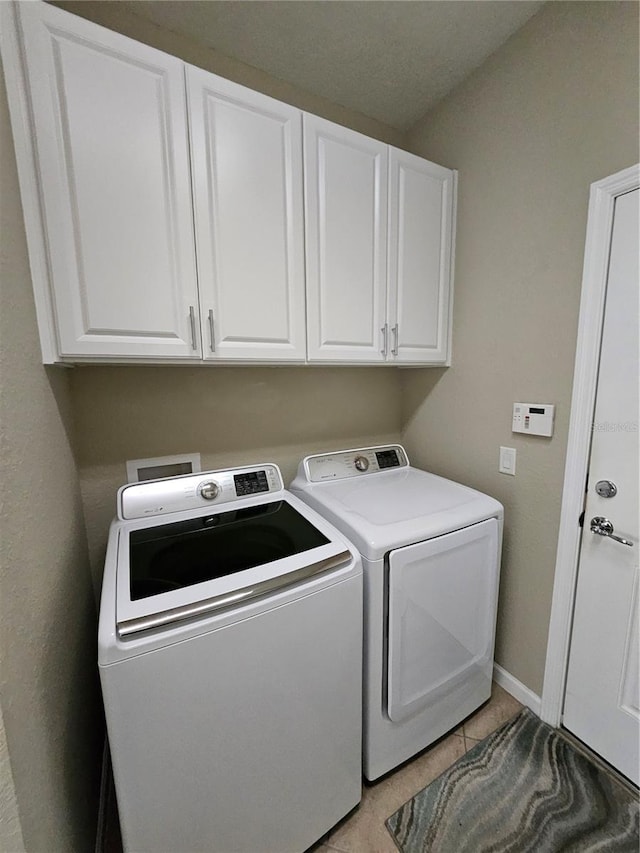 clothes washing area with washer and clothes dryer and cabinets