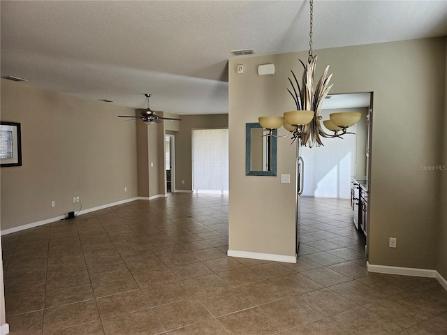 unfurnished room featuring ceiling fan with notable chandelier, dark tile patterned floors, and a textured ceiling