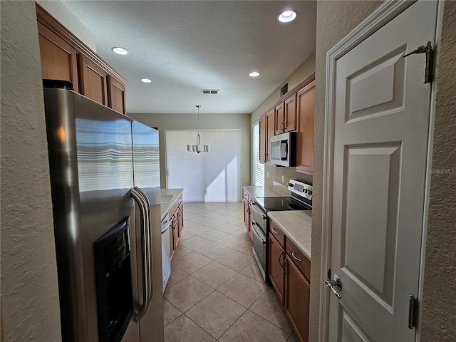 kitchen featuring appliances with stainless steel finishes, a textured ceiling, light tile patterned floors, decorative light fixtures, and an inviting chandelier