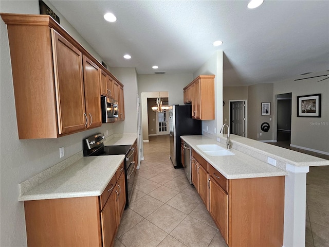 kitchen with sink, stainless steel appliances, kitchen peninsula, light tile patterned floors, and ceiling fan with notable chandelier