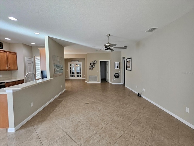 interior space featuring ceiling fan, light tile patterned flooring, a textured ceiling, and french doors