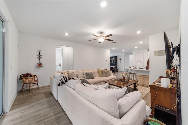 living room with ceiling fan, light hardwood / wood-style flooring, and sink