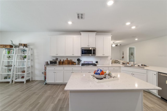 kitchen with light stone countertops, sink, stainless steel appliances, and white cabinetry