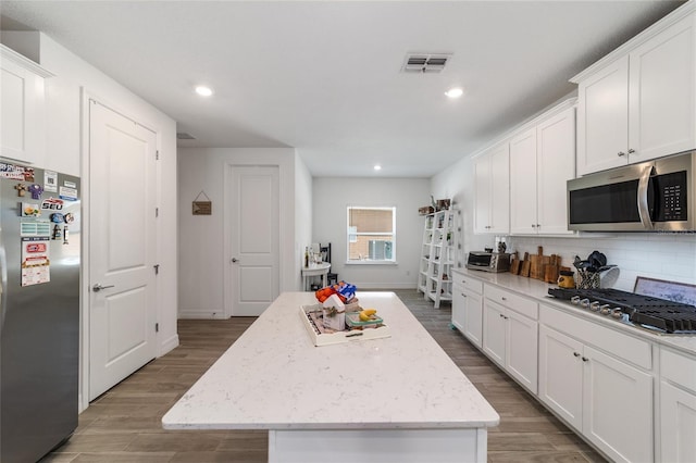 kitchen with white cabinetry, hardwood / wood-style flooring, stainless steel appliances, and a center island