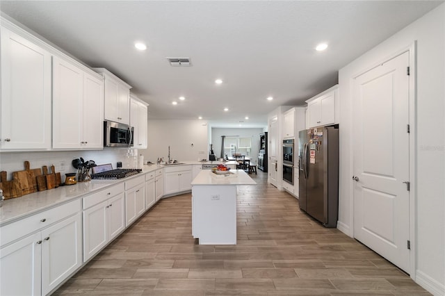 kitchen featuring a center island, kitchen peninsula, sink, white cabinetry, and stainless steel appliances