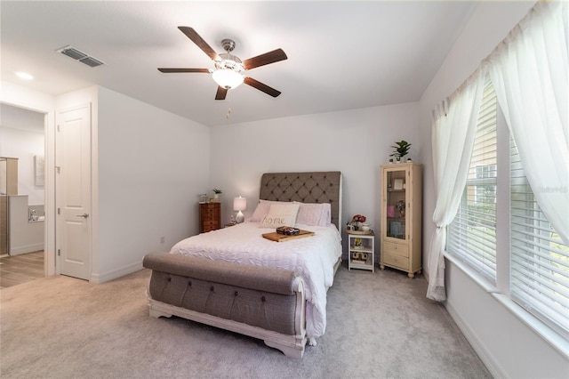 bedroom with ceiling fan, light colored carpet, and multiple windows