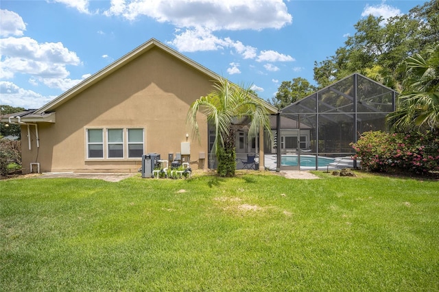 back of house with an outdoor pool, glass enclosure, a yard, and stucco siding