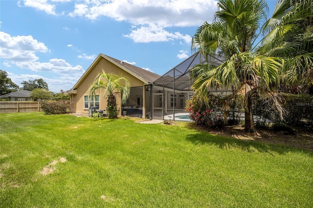 back of property featuring a yard, stucco siding, glass enclosure, fence, and an outdoor pool