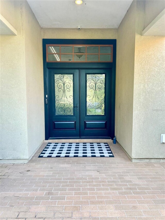 property entrance with stucco siding and french doors