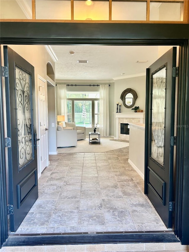 entryway with baseboards, crown molding, and a glass covered fireplace