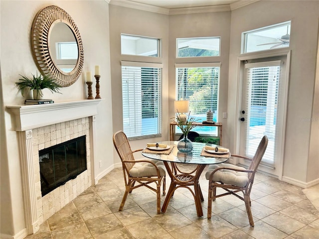 dining area with baseboards, ornamental molding, and a tile fireplace