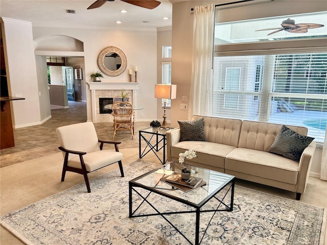 carpeted living room featuring visible vents, a ceiling fan, a high end fireplace, ornamental molding, and baseboards