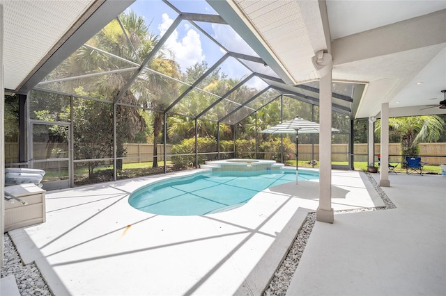 view of pool featuring glass enclosure, a patio area, a fenced backyard, and a pool with connected hot tub