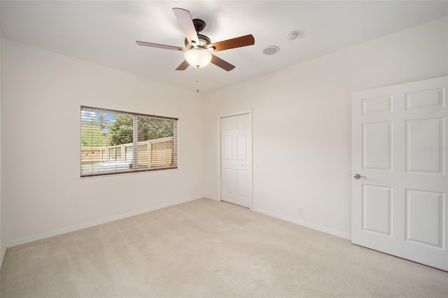 spare room with light carpet, ceiling fan, and baseboards