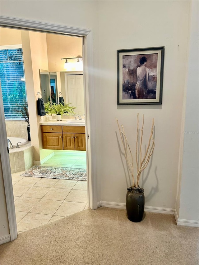 hall with light tile patterned floors, baseboards, and light colored carpet