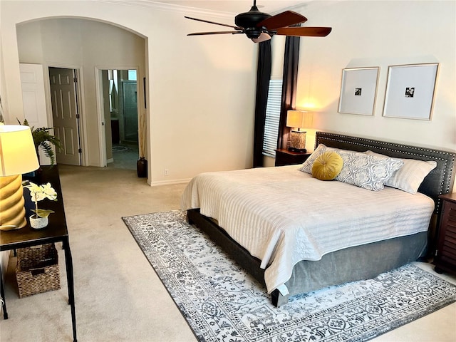 bedroom with baseboards, arched walkways, light colored carpet, ensuite bath, and ornamental molding