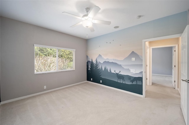 carpeted spare room with ceiling fan and baseboards