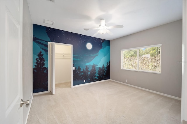 carpeted empty room with ceiling fan, an accent wall, and baseboards