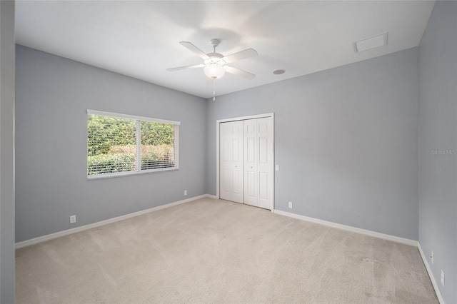 unfurnished bedroom featuring a ceiling fan, baseboards, a closet, and light colored carpet