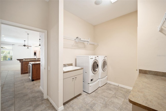 clothes washing area featuring laundry area, washing machine and dryer, baseboards, and a sink