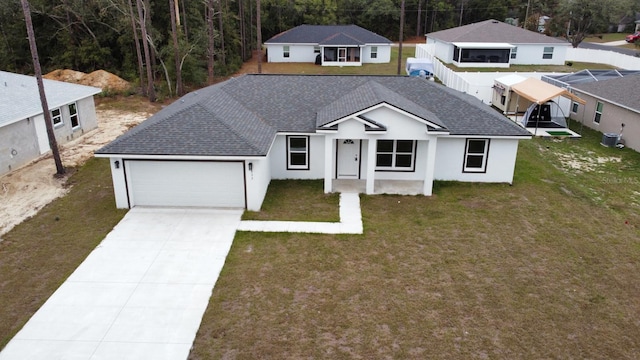 view of front facade featuring cooling unit, a garage, and a front lawn