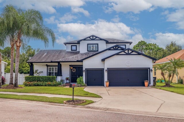 view of front of property with ceiling fan, a front yard, and a garage