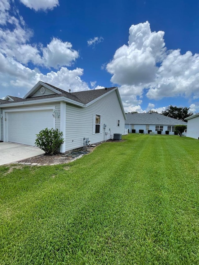 view of home's exterior with a garage, cooling unit, and a lawn