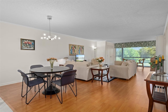 dining room with an inviting chandelier, a textured ceiling, and light wood-type flooring