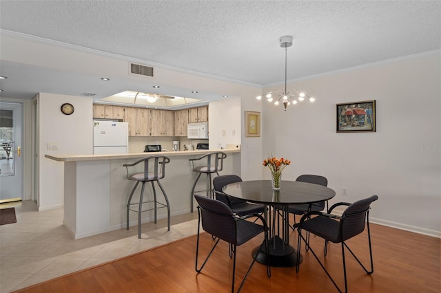 dining space featuring crown molding, a textured ceiling, and light hardwood / wood-style flooring