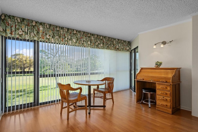 dining space with a textured ceiling, wood-type flooring, and plenty of natural light