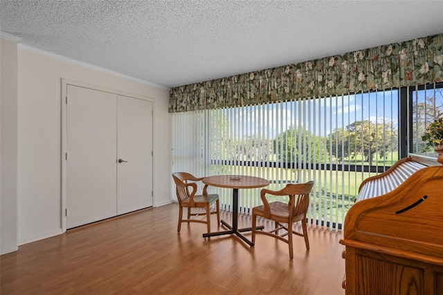 dining room with ornamental molding, hardwood / wood-style floors, and a textured ceiling