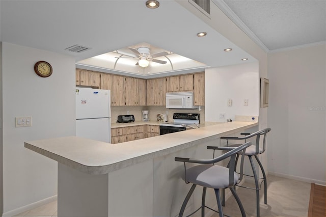 kitchen with a kitchen bar, kitchen peninsula, ceiling fan, and white appliances