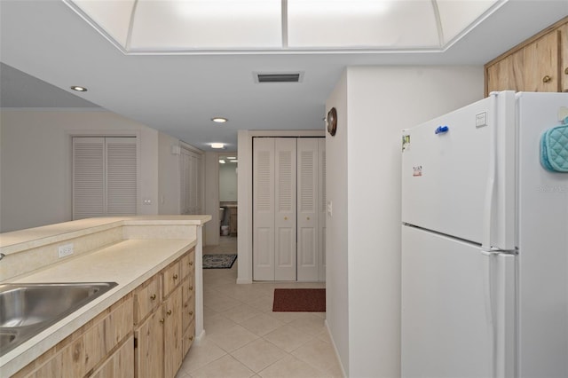 kitchen featuring sink, white refrigerator, light tile patterned floors, and light brown cabinets