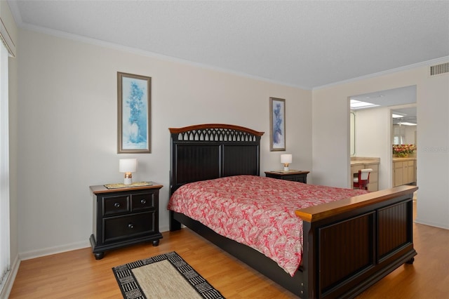 bedroom featuring light hardwood / wood-style floors, ensuite bathroom, and crown molding