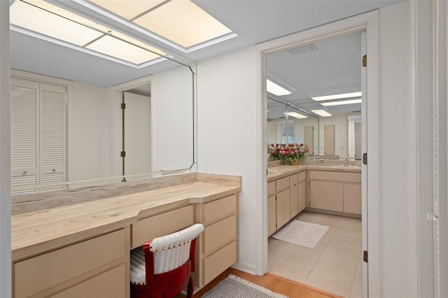 bathroom with tile patterned flooring, vanity, and a skylight