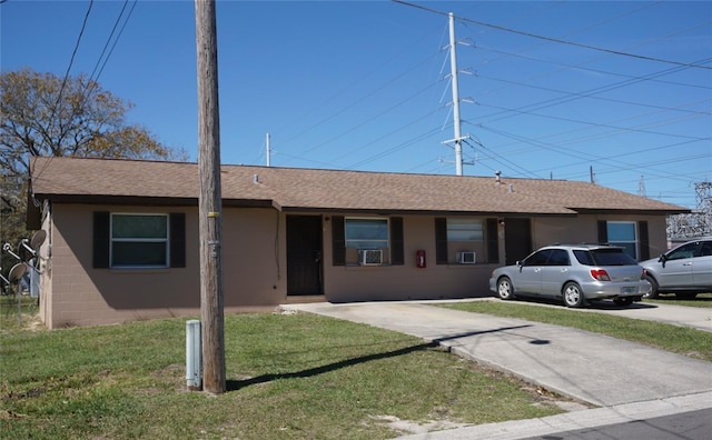 ranch-style house with a front lawn, roof with shingles, and concrete block siding