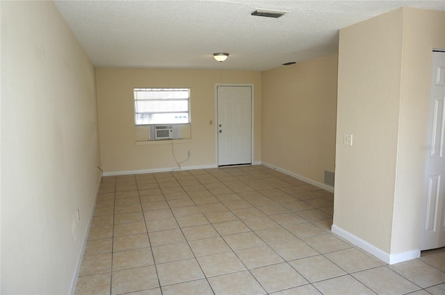 unfurnished room with light tile patterned floors, visible vents, baseboards, cooling unit, and a textured ceiling