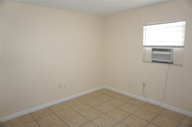 spare room with cooling unit, light tile patterned flooring, and baseboards