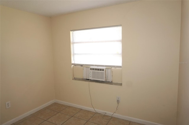 spare room featuring cooling unit, baseboards, and light tile patterned floors