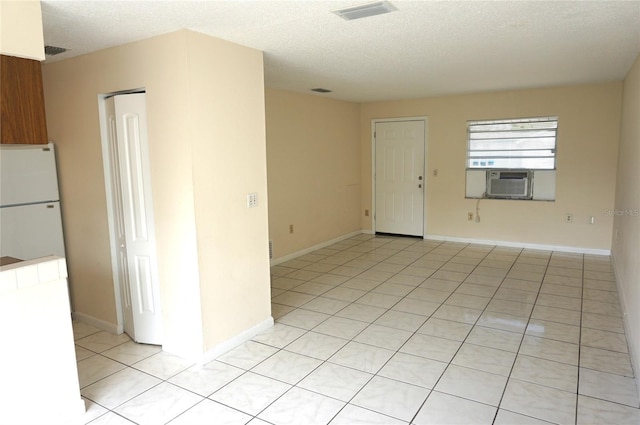 unfurnished room featuring visible vents, a textured ceiling, baseboards, and light tile patterned flooring